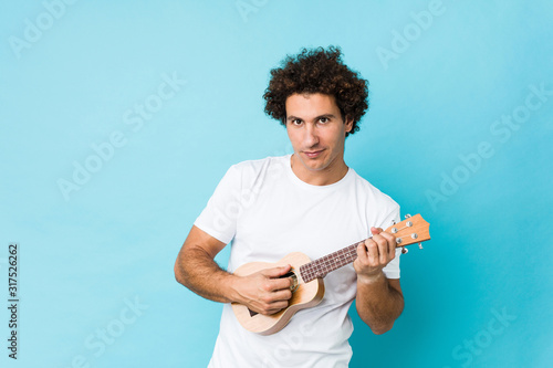 Young caucasian man happy playing ukelele isolated