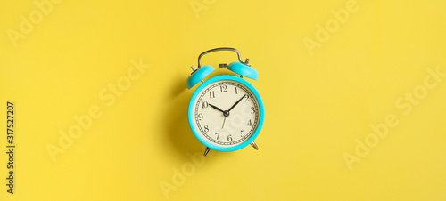 Turquoise vintage alarm clock on yellow background. Top view. Flat lay