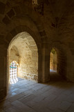 Interior of ancient stone building with bright sunlight shining through arches