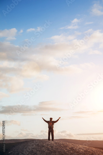 The guy climbed to the top of the mountain and raised his hands to the sky