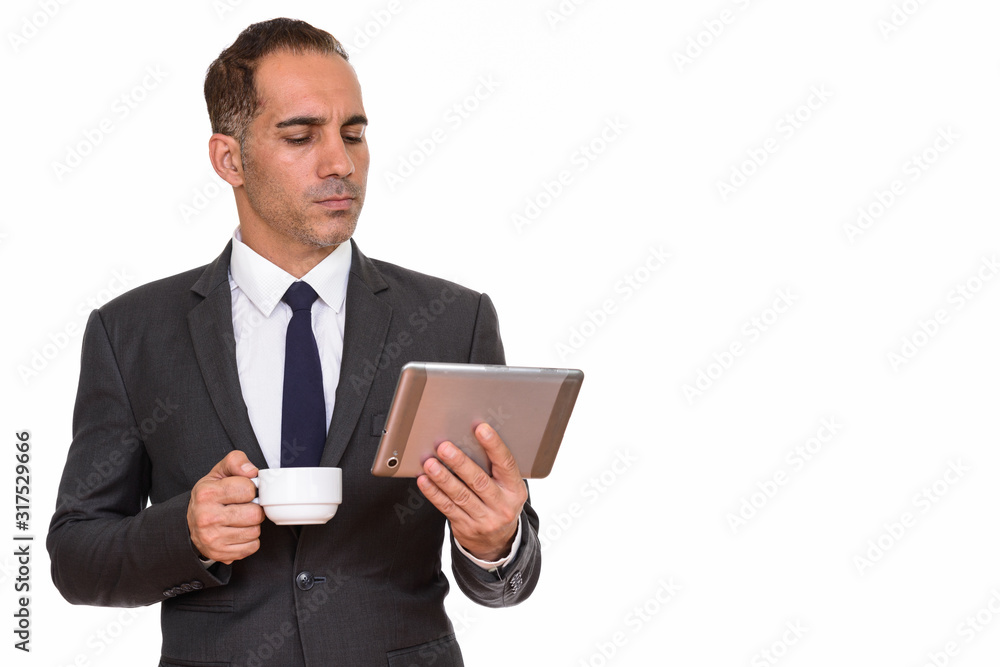 Mature Persian businessman drinking coffee while using digital tablet
