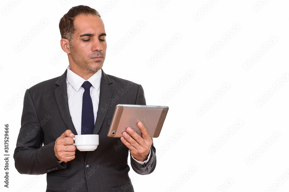Mature Persian businessman drinking coffee while using digital tablet Mature Persian businessman drinking coffee while using digital tablet