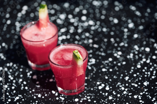 Summer cocktail with watermelon on black metal surface.