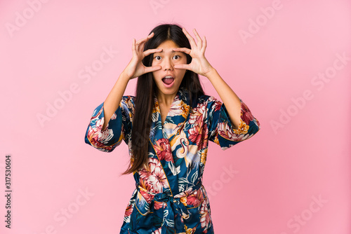Fotografija Young asian woman wearing a kimono pajamas keeping eyes opened to find a success opportunity