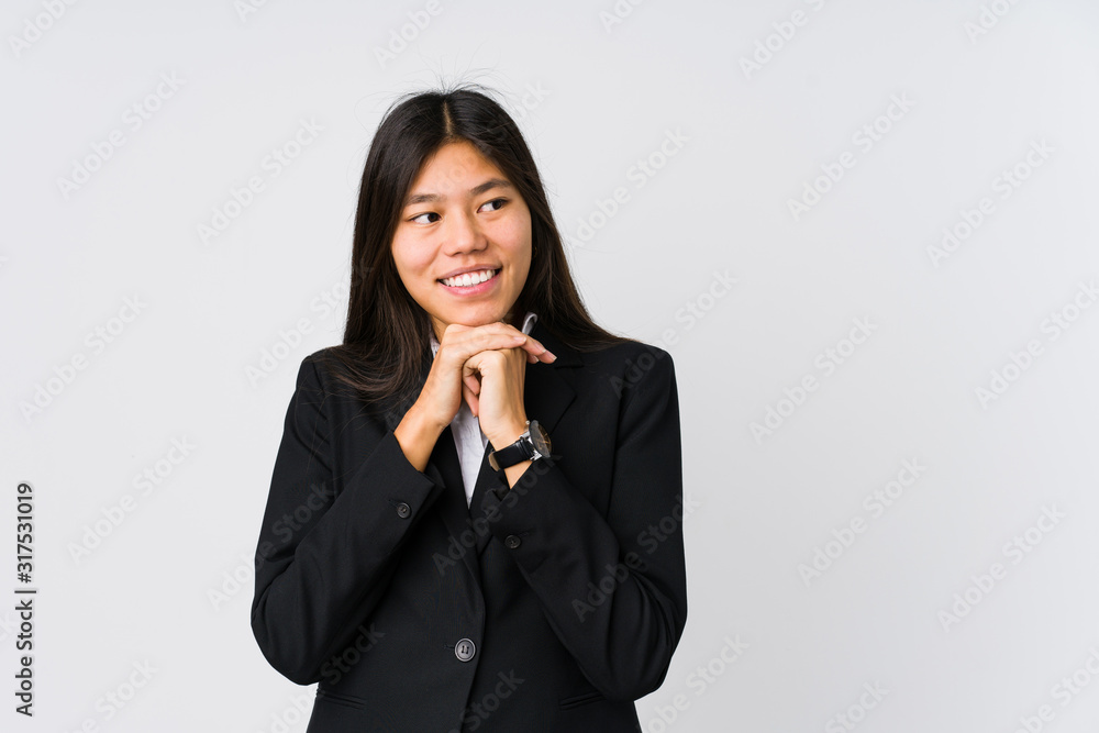 Young asian business woman keeps hands under chin, is looking happily aside. Young asian business woman keeps hands under chin, is looking happily aside.