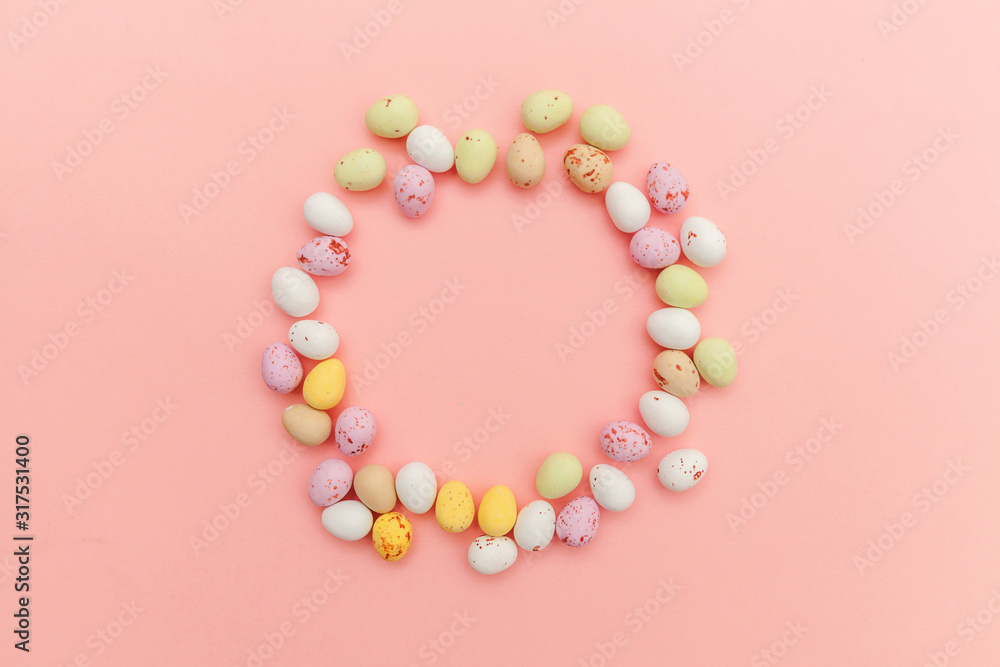 Happy Easter concept. Easter candy chocolate eggs and jellybean sweets isolated on trendy pastel pink background. Simple minimalism flat lay top view copy space