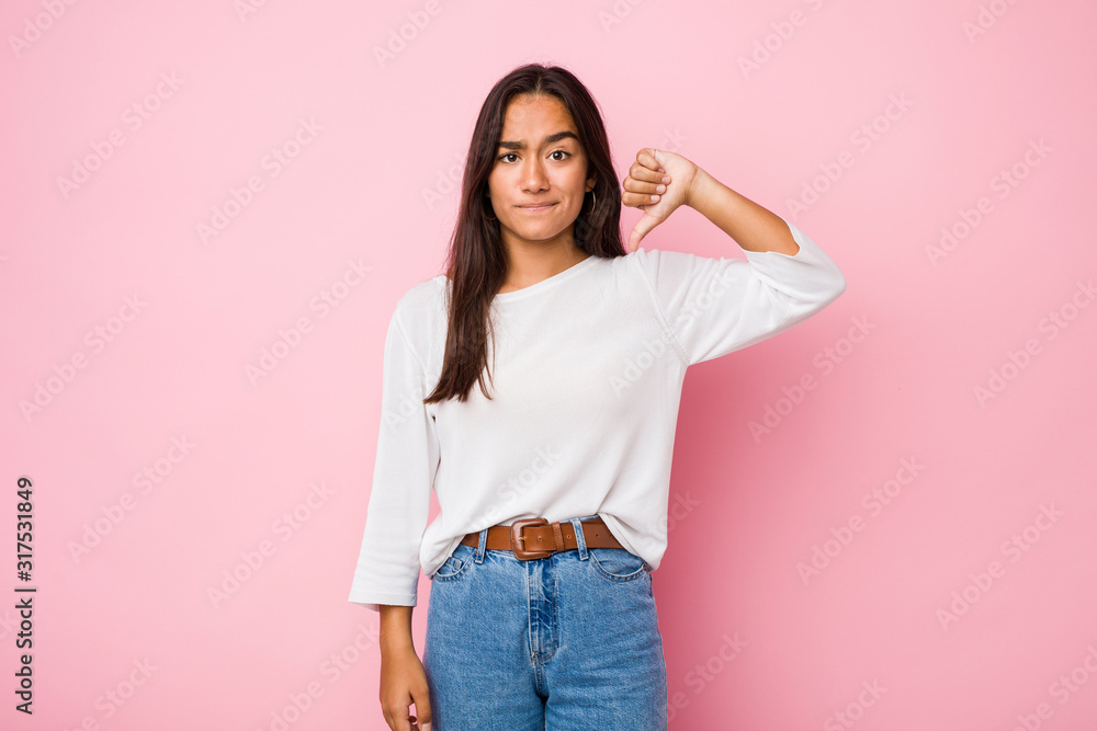 Young mixed race indian woman showing a dislike gesture, thumbs down. Disagreement concept.