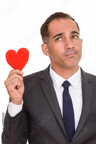 Mature Persian businessman thinking while holding heart ready for Valentine's day © Ranta Images