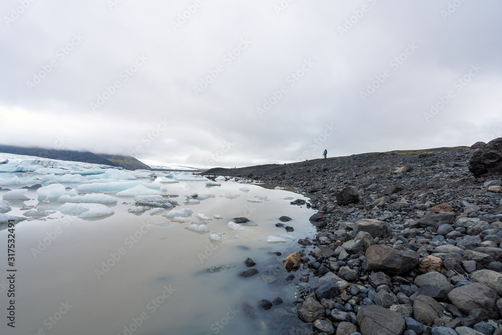 Girl photographer by Fjallsarlon glacier lagoon at the end of Vatnajokull glacier. Icebergs reflects in the calm water. Foggy weather. Girl photographer by Fjallsarlon glacier lagoon at the end of Vatnajokull glacier. Icebergs reflects in the calm water. Foggy weather.