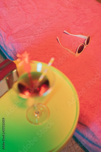 Fototapeta Naklejka Na Ścianę i Meble -  Sunglasses on sunbed with yellow table and cocktail drink and portable radio next to it.