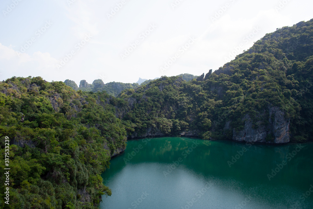 Scenic view on a lake surrounded by rocky mountain hills covered with trees on tropical island Ko Mae Ko within Ang Thong national marine park archipelago