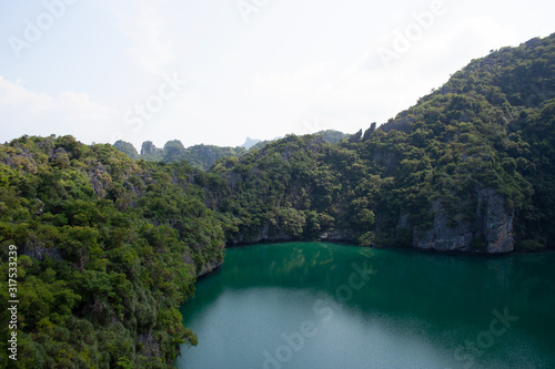 Scenic view on a lake surrounded by rocky mountain hills covered with trees on tropical island Ko Mae Ko within Ang Thong national marine park archipelago
