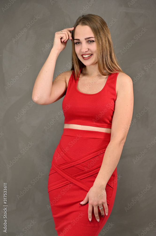 Vertical photo of a pretty smiling girl with long hair and great makeup in a red dress with emotions in different poses. Universal concept of a female portrait. Vertical photo of a pretty smiling girl with long hair and great makeup in a red dress with emotions in different poses. Universal concept of a female portrait.