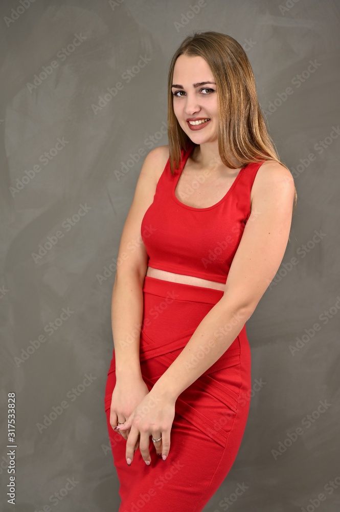Vertical photo of a pretty smiling girl with long hair and great makeup in a red dress with emotions in different poses. Universal concept of a female portrait. Vertical photo of a pretty smiling girl with long hair and great makeup in a red dress with emotions in different poses. Universal concept of a female portrait.