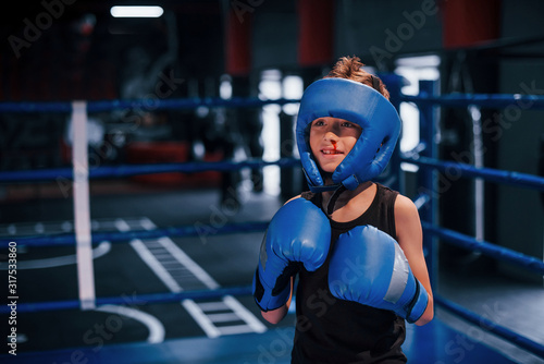 Little boy in protective wear and with nose bleed training in the boxing ring