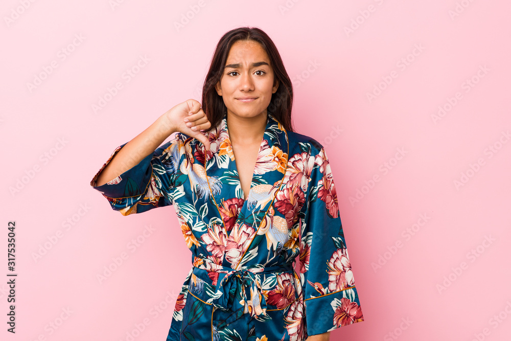 Young indian woman wearing a kimono pajama showing a dislike gesture, thumbs down. Disagreement concept. Young indian woman wearing a kimono pajama showing a dislike gesture, thumbs down. Disagreement concept.