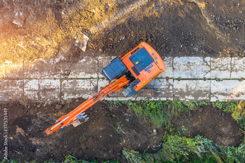 Excavator on caterpillars in the foundation pit during the construction of the building foundation, digging. Aerial top view.