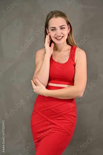 Universal concept of a female portrait. Vertical photo of a pretty smiling girl with long hair and great makeup in a red dress with emotions in different poses.