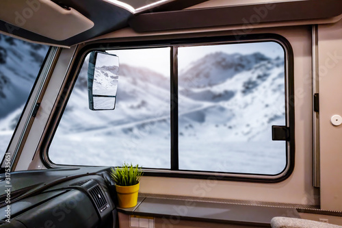 Winter camper with big window and free space for your decoration.Mountains with sun light and snow flakes  © magdal3na