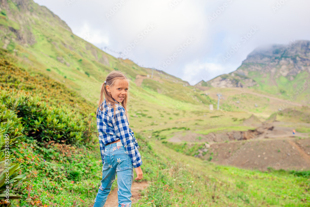 Beautiful happy little girl in mountains in the background of fog