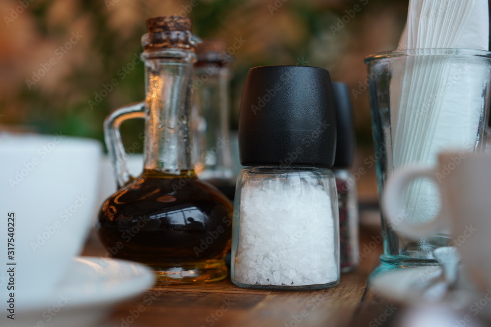 Bottle with vinegar, salt and napkins on a wooden table in a restaurant.