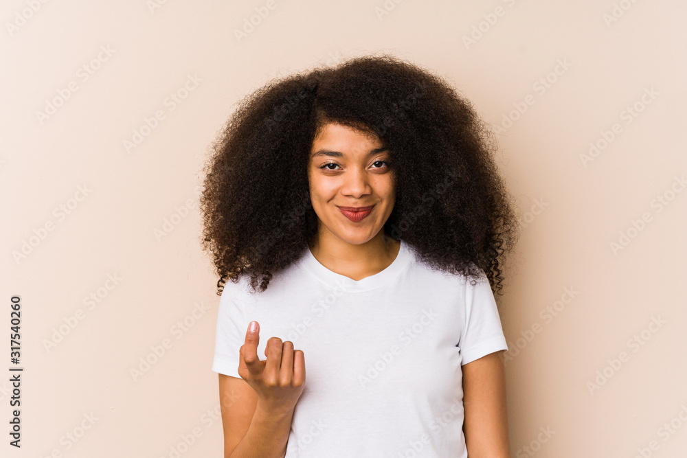 Young african american woman pointing with finger at you as if inviting come closer. Young african american woman pointing with finger at you as if inviting come closer.