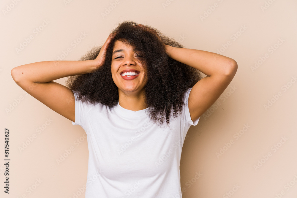 Young african american woman laughs joyfully keeping hands on head. Happiness concept. Young african american woman laughs joyfully keeping hands on head. Happiness concept.