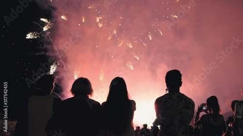 People silhouettes on a background of fireworks. group of people enjoying the city night view and fireworks