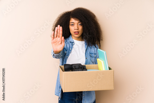 Young afro woman moving home isolated Young afro woman standing with outstretched hand showing stop sign, preventing you. © Asier