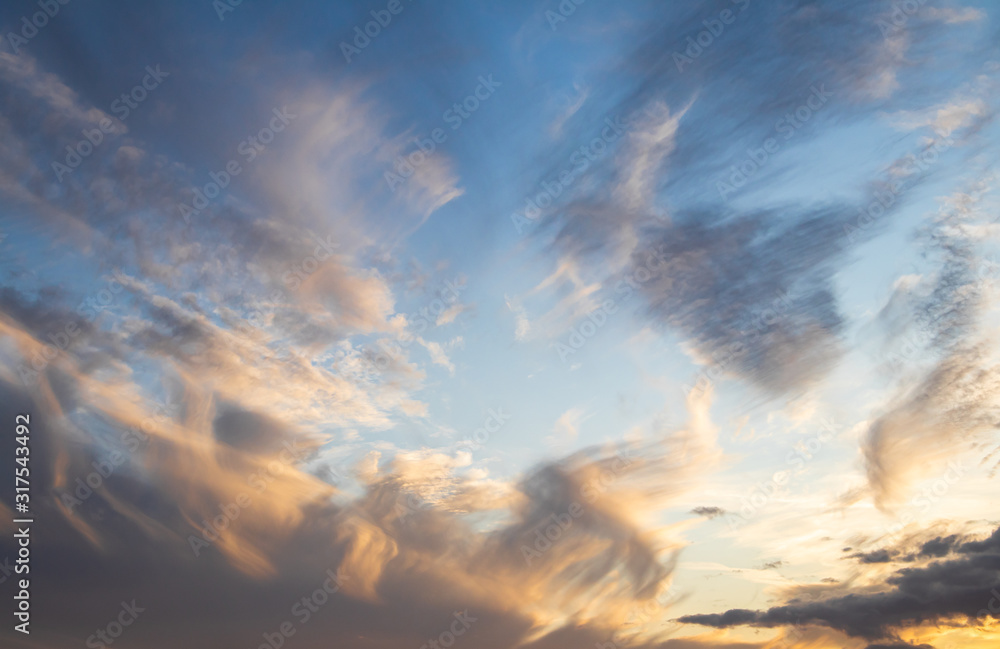 The evening sky with orange sunlight and white clouds.