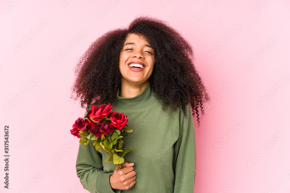 Young afro woman holding a roses isolated Young afro woman holding a roseslaughing and having fun. Young afro woman holding a roses isolated Young afro woman holding a roseslaughing and having fun.