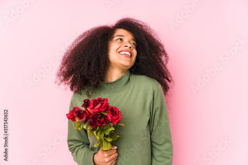 Young afro woman holding a roses isolated Young afro woman holding a rosesdreaming of achieving goals and purposes