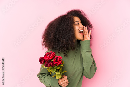 Young afro woman holding a roses isolated Young afro woman holding a rosesshouting and holding palm near opened mouth.