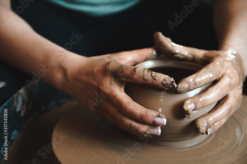 Pottery concept. Professional ceramist working with clay at throwing table in workshop.