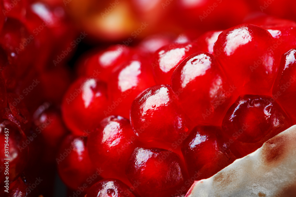 Red ripe and juicy seeds of fresh pomegranate fruit close-up.