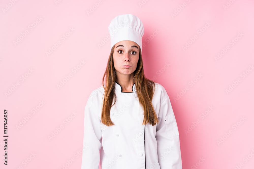 Young caucasian chef woman isolated shrugs shoulders and open eyes confused. Young caucasian chef woman isolated shrugs shoulders and open eyes confused.