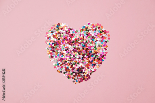 Valentine day composition with heart made from confetti on pink background, flat lay