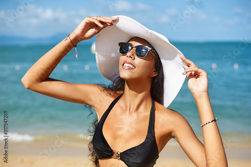 Beautiful woman in hat and sunglasses enjoing summer on a beach