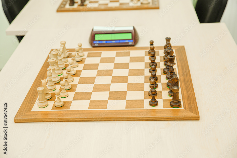 Chess board with aligned figures and a clock before the game Chess board with aligned figures and a clock before the game
