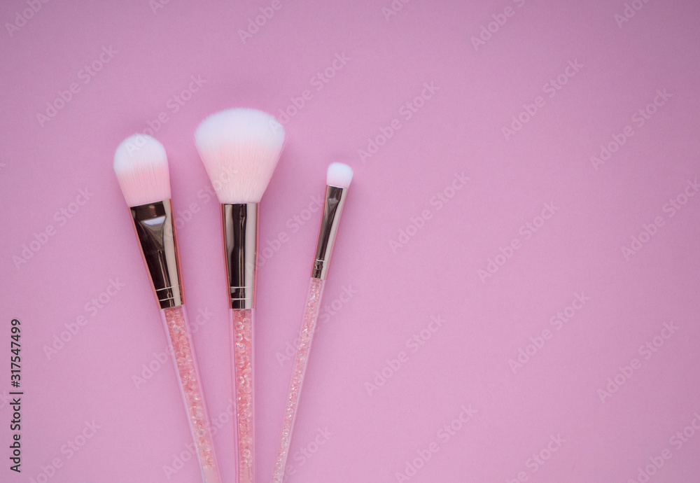 Set of pink cosmetic nylon makeup brushes on pink background with copy space. Foundation, powder and blush, eye shadow brush top view. Handles filled with rose quartz. Professional make-up accessories Set of pink cosmetic nylon makeup brushes on pink background with copy space. Foundation, powder and blush, eye shadow brush top view. Handles filled with rose quartz. Professional make-up accessories