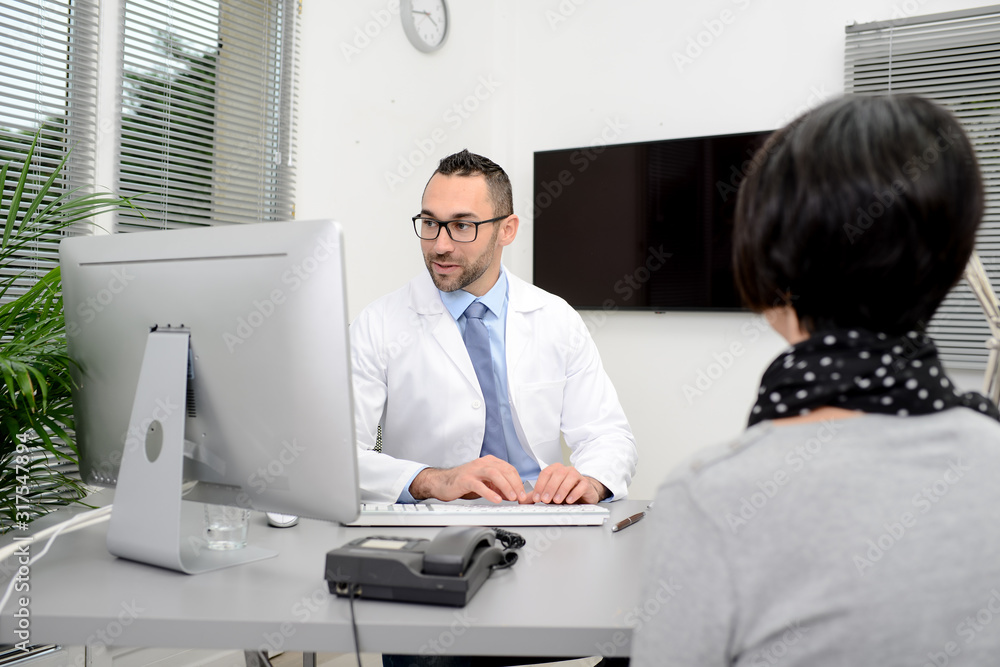 handsome male doctor with a female patient in hospital consultation office desk