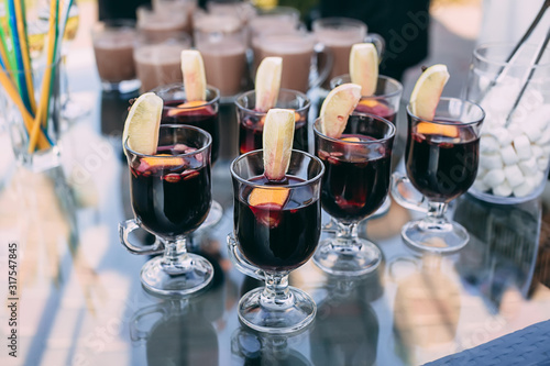 Red spicy mulled wine in glasses with orange slices on the holiday table