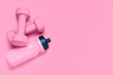 Fitness workout background concept with pink dumbbells and bottle of water. Top view flatlay sport, diet and healthy lifestyle with training equipment on pink background with blank copy space.