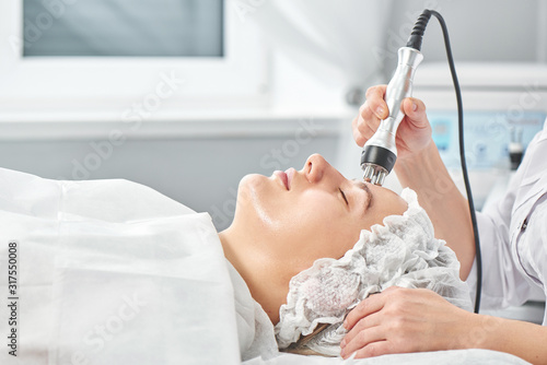Fotografie Professional beautician in office conducts session of thermal or radio frequency hardware RF lifting