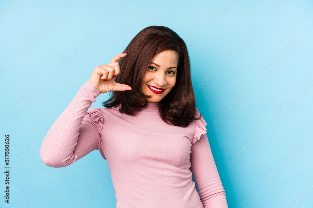 Middle age latin woman isolated holding something little with forefingers, smiling and confident. Middle age latin woman isolated holding something little with forefingers, smiling and confident.
