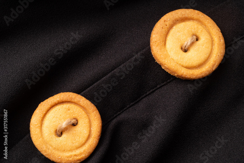 Cookies button with threads, on a black background, fabric, shirt.