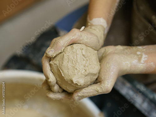 Photography of the clay soiled hands with clay ball preparing for crafting work. Concepts of handicraft. Arts school. View from above / top view.