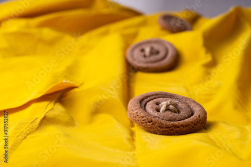 Cookies button with threads on a yellow cloak. Arranged in a row.
