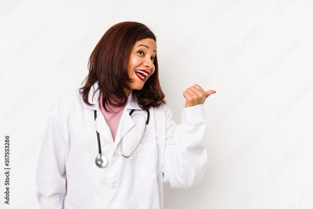 Middle age latin doctor woman isolated points with thumb finger away, laughing and carefree. Middle age latin doctor woman isolated points with thumb finger away, laughing and carefree.