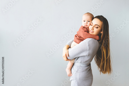 Happy mother holding up her baby girl. Young beautiful mother holds her baby and cuddles, motherhood concept